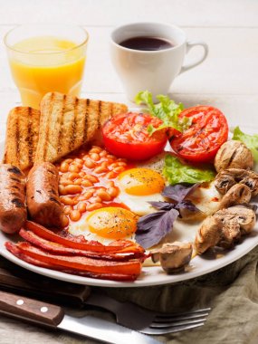 Tam İngiliz kahvaltısı dahil sosis, ızgara domates ve mantar, yumurta, pastırma, Kuru fasulye, ekmek ile portakal suyu