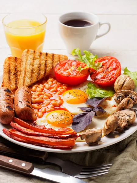 Englisches Frühstück mit Würstchen, gegrillten Tomaten und Pilzen, Ei, Speck, gebackenen Bohnen, Brot mit Orangensaft — Stockfoto