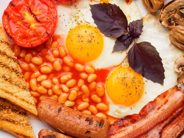 Desayuno inglés completo con salchichas, tomates y champiñones a la parrilla, huevo, tocino, frijoles horneados, pan con jugo de naranja —  Fotos de Stock