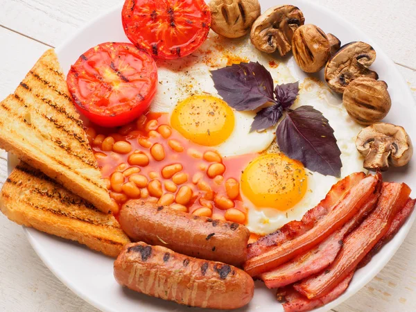 Desayuno inglés completo con salchichas, tomates y champiñones a la parrilla, huevo, tocino, frijoles horneados, pan con jugo de naranja — Foto de Stock