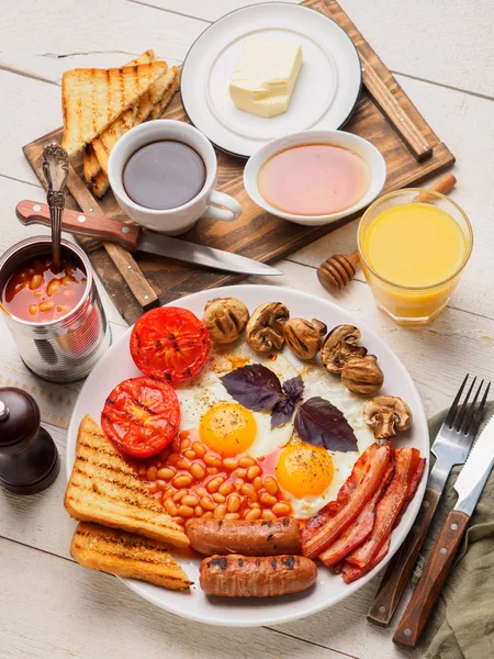 Teljes angol reggeli kolbász, sült paradicsom és gomba, tojás, szalonna, sült bab, kenyér, narancslé — Stock Fotó