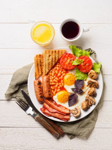 Englisches Frühstück mit Würstchen, gegrillten Tomaten und Pilzen, Ei, Speck, gebackenen Bohnen, Brot mit Orangensaft — Stockfoto