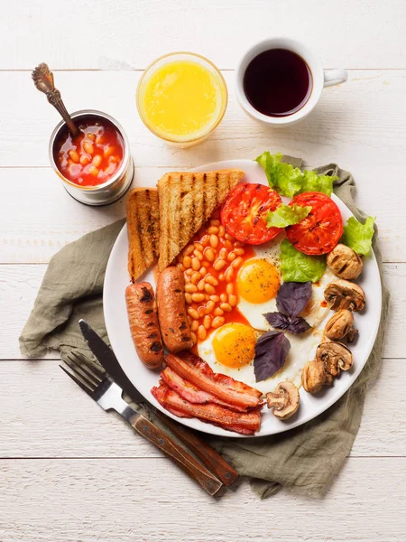 Desayuno inglés completo con salchichas, tomates y champiñones a la parrilla, huevo, tocino, frijoles horneados, pan con jugo de naranja — Foto de Stock