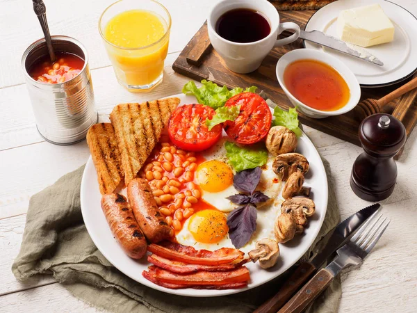 Desayuno inglés completo con salchichas, tomates y champiñones a la parrilla, huevo, tocino, frijoles horneados, pan con jugo de naranja — Foto de Stock