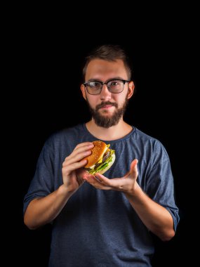 genç adam siyah izole bir lokanta hamburger yeme