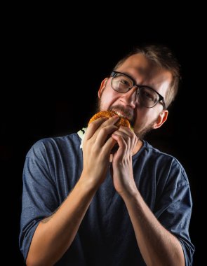 genç adam siyah izole bir lokanta hamburger yeme