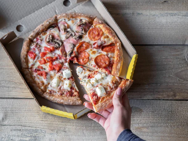Pizza in delivery box on wooden table