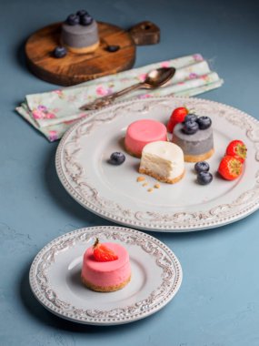 Küçük berry cheesecakes plaka ve mavi arka plan üzerinde yuvarlak