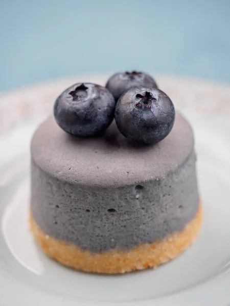 Små runda bär cheesecakes på plattan och blå bakgrund — Stockfoto