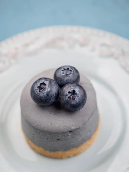 Mały okrągły berry serniki na talerz i niebieskie tło — Zdjęcie stockowe