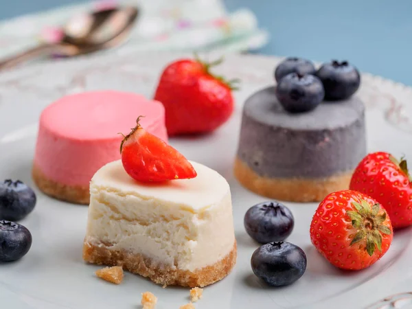 Små runda bär cheesecakes på plattan och blå bakgrund — Stockfoto