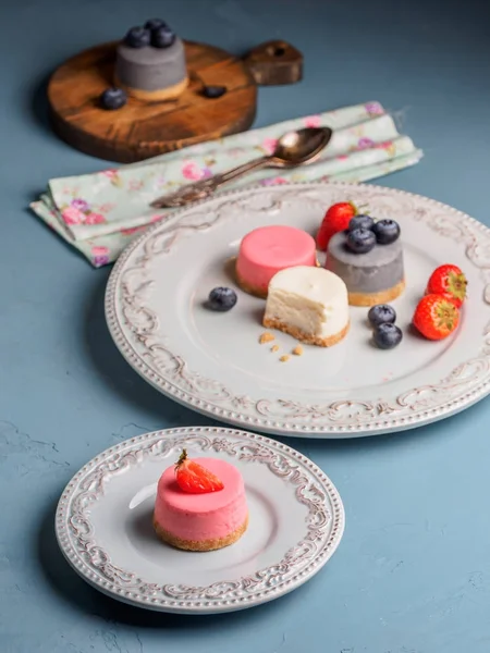 Küçük berry cheesecakes plaka ve mavi arka plan üzerinde yuvarlak