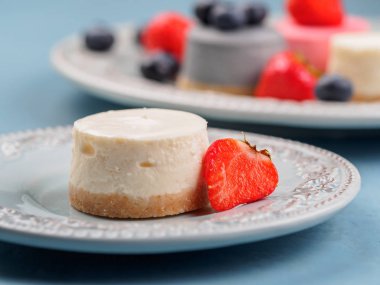Küçük berry cheesecakes plaka ve mavi arka plan üzerinde yuvarlak