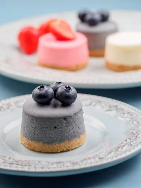 Små runda bär cheesecakes på plattan och blå bakgrund — Stockfoto