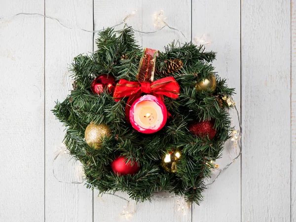 Christmas spruce branch wreath with candle on the wood board