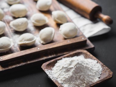 Donmuş çiğ hamur köfteleri siyah arka plandaki ahşap masada.