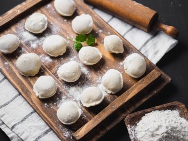 Donmuş çiğ hamur köfteleri siyah arka plandaki ahşap masada.