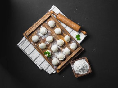 Donmuş çiğ hamur köfteleri siyah arka plandaki ahşap masada.