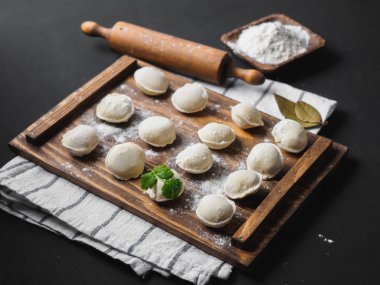 Donmuş çiğ hamur köfteleri siyah arka plandaki ahşap masada.