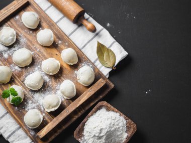 Donmuş çiğ hamur köfteleri siyah arka plandaki ahşap masada.