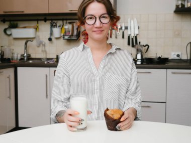 Genç kız yiyor muffin mutfak gülümsemek