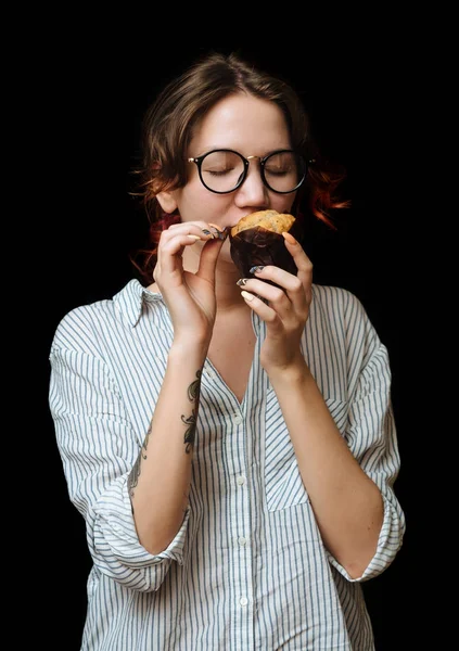 Joven sonrisa chica con muffin en el fondo negro — Foto de Stock