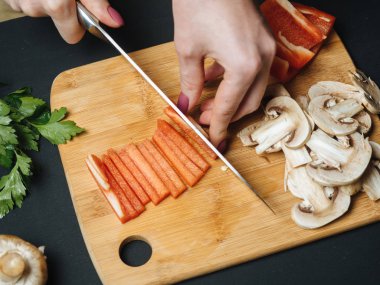 Kadın kesme çiğ kırmızı biber ahşap tahta üzerinde