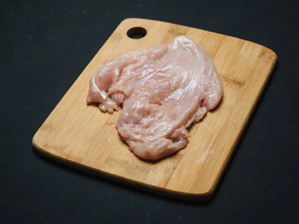 木板上的生鸡肉鱼片。黑色背景 — 图库照片