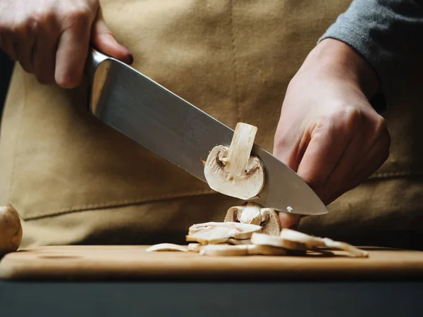 Vrouw snijden rauwe paddestoelen op een houten bord — Stockfoto