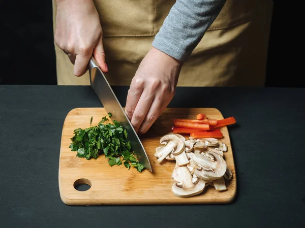 Vrouw snijden peterselie Groenen op houten bord — Stockfoto