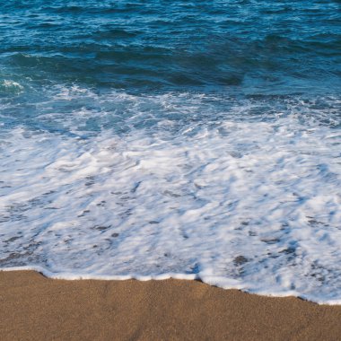 Deniz okyanus plaj. Mavi su köpük ve ayak izleri ile