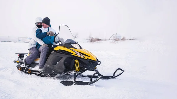 Um par de homens e mulheres na moto de neve. Campo de neve de inverno — Fotografia de Stock