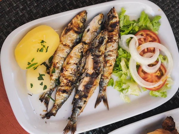 Рыба и вареный картофель с овощами на тарелке — стоковое фото