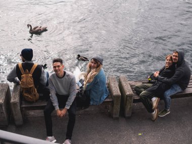 Turistler banklar kuğular ile su Nehri yakınında