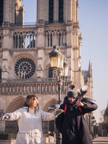 Tourists feeding pigeons in the square in front of the cathedral of Notre Dame — Stock Photo, Image