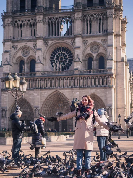 Tourists feeding pigeons in the square in front of the cathedral of Notre Dame — Stock Photo, Image