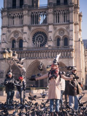 Paris, Fransa - 20 Ocak 2017: turist Notre Dame Katedrali önünde meydanında güvercin besleme. Paris, Fransa