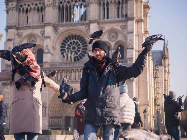 Turisti che nutrono piccioni nella piazza antistante la cattedrale di Notre Dame — Foto Stock