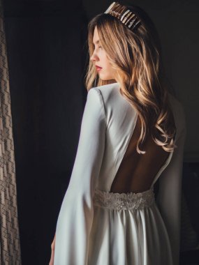 Geri pencere yakınındaki beyaz elbiseli genç gelin 