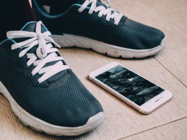 Kırık ekran smartphone üzerinde ayakkabı ile seramik zemin