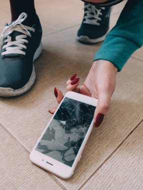 Kırık ekran smartphone üzerinde ayakkabı ile seramik zemin