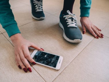 Kırık ekran smartphone üzerinde ayakkabı ile seramik zemin