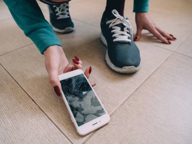 Kırık ekran smartphone üzerinde ayakkabı ile seramik zemin