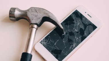 kırık ekran beyaz masa üzerinde çekiç ile Smartphone