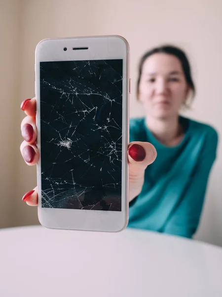 Broken glass screen smartphone in hand, white background