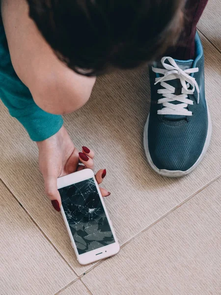 Kırık ekran smartphone karo zemin üzerinde kızla 