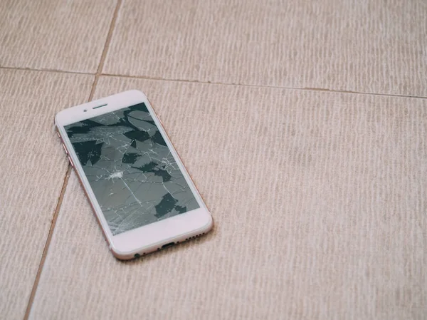 Broken screen smartphone on the floor tile