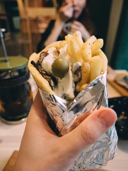 Gyros daging Yunani dengan saus, sayuran, keju feta dan kentang goreng di tangan — Stok Foto