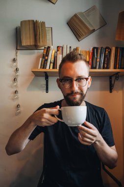 Elinde büyük beyaz kahve fincanı olan adam.