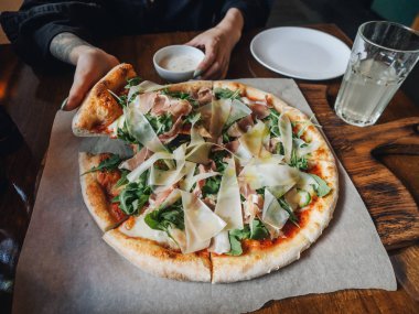 Parma jambonlu pizza, peynir, roka, kırsal kafe masasında sos.